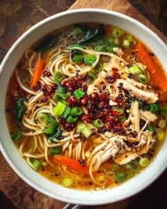 Aromatic bowl of Ginger Garlic Chicken Soup with noodles, garnished with herbs.