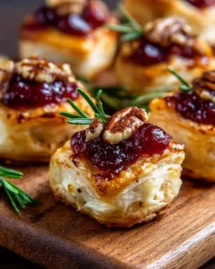 Baked cranberry brie bites served on a platter with fresh herbs for garnish