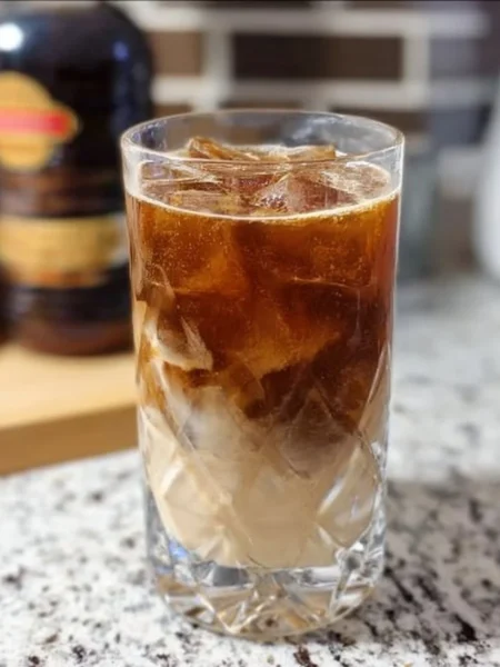 Creamy Root Beer Rum Cocktail served in a glass with ice and a straw