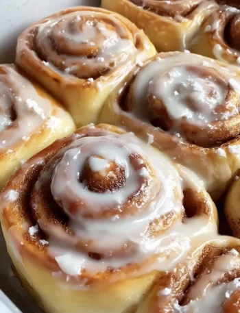 Freshly baked homemade cinnamon rolls topped with creamy icing