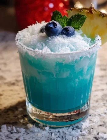 Jack Frost Cocktail garnished with mint and blueberries in a glass, ideal for winter parties.