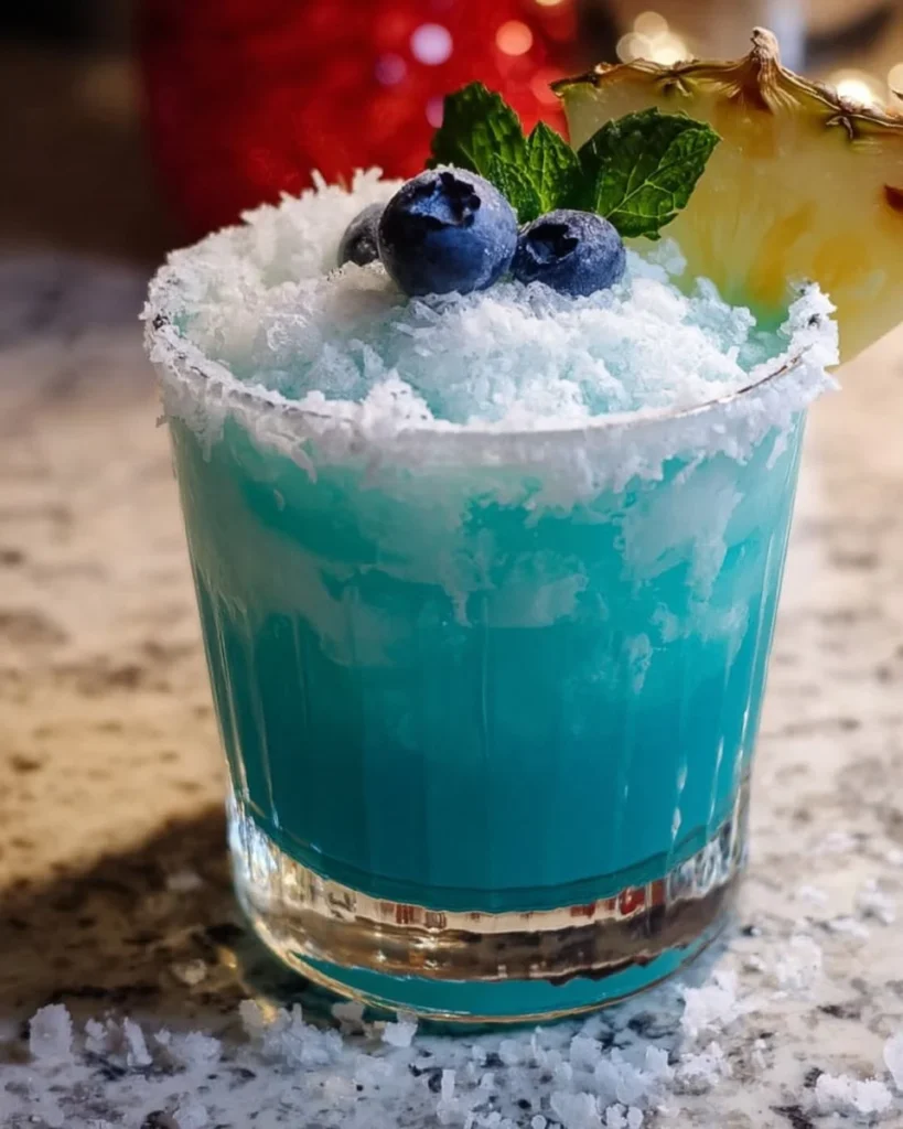 Jack Frost Cocktail garnished with mint and blueberries in a glass, ideal for winter parties.