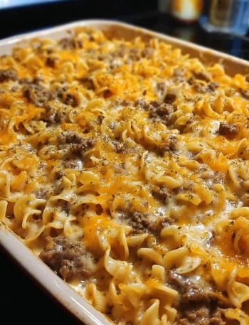 Sour cream beef noodle casserole topped with cheese and herbs in a baking dish