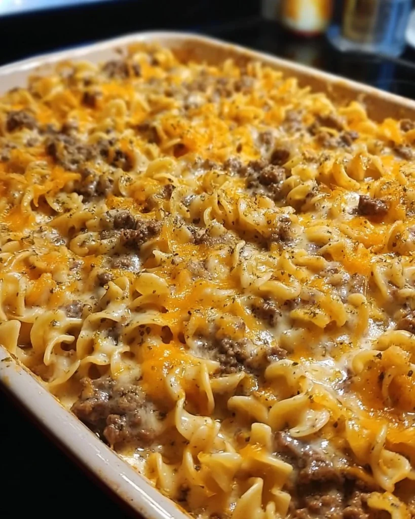 Sour cream beef noodle casserole topped with cheese and herbs in a baking dish