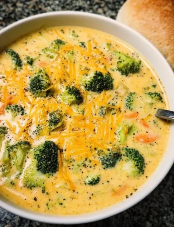 Delicious bowl of creamy broccoli cheddar soup topped with cheese and broccoli florets.