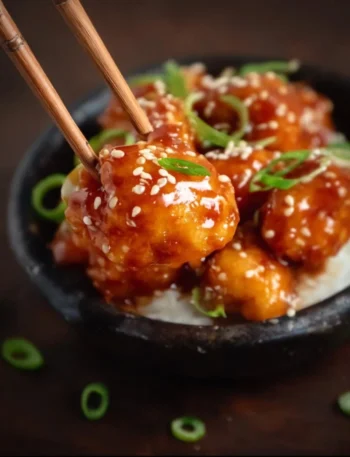 Plate of Honey Sesame Chicken garnished with sesame seeds and green onions